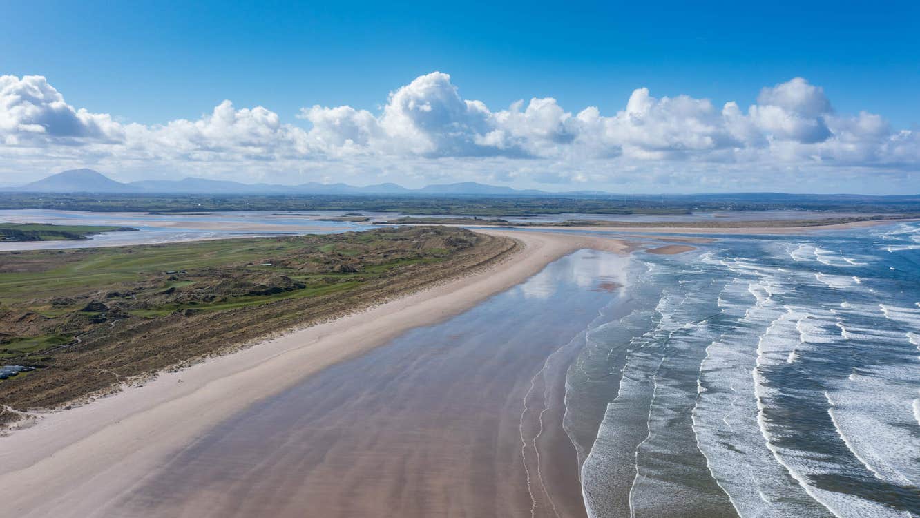 Long sandy beach with the sea and blue sky with white clouds