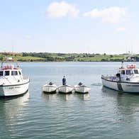 Two small fishing vessels with three smaller self drive boats moored between them