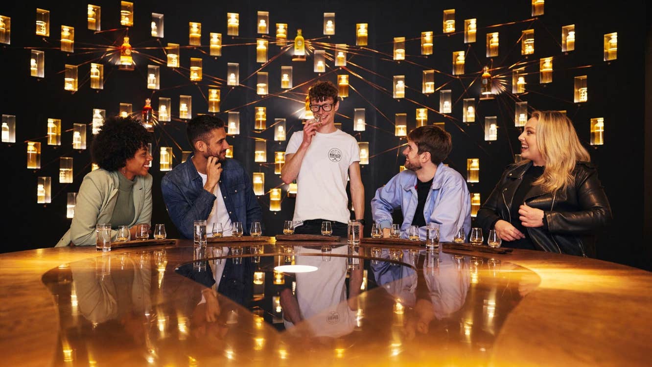 A small group of people at a table with whiskey glasses in front of them