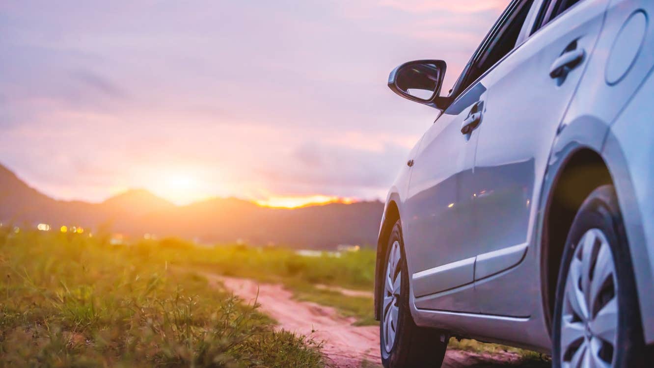 Small car on a country lane facing the setting sun