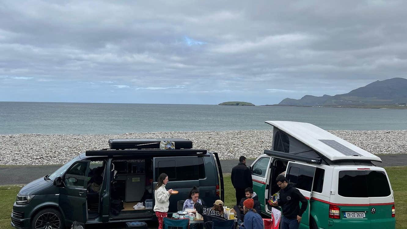 A group of people having a picnic beside two camper vans