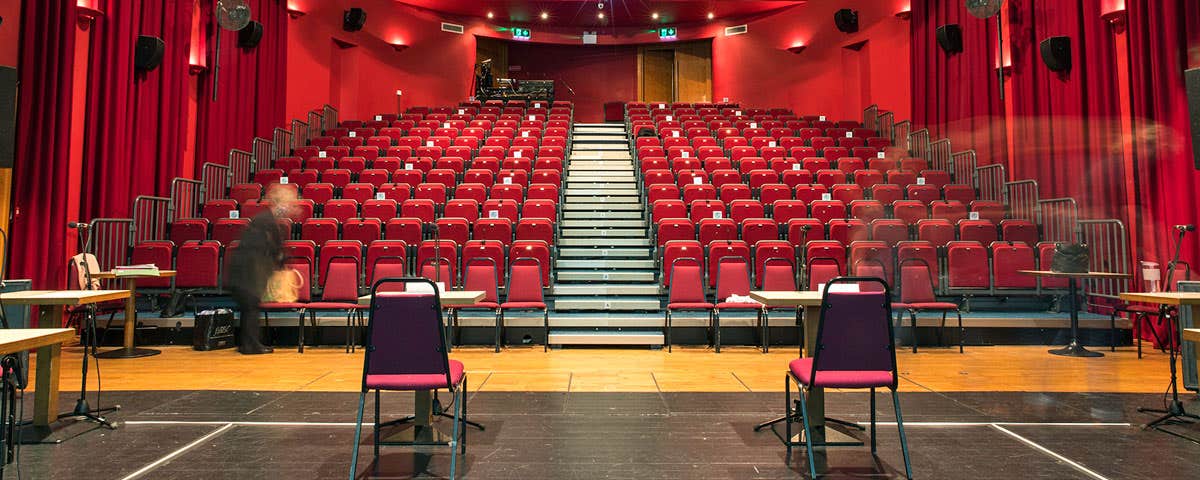 Interior of theatre at Dunamaise Arts Centre from stage facing read theatre style seating layout surrounded by red drapes