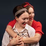 Two women in 1960s vintage clothes hugging