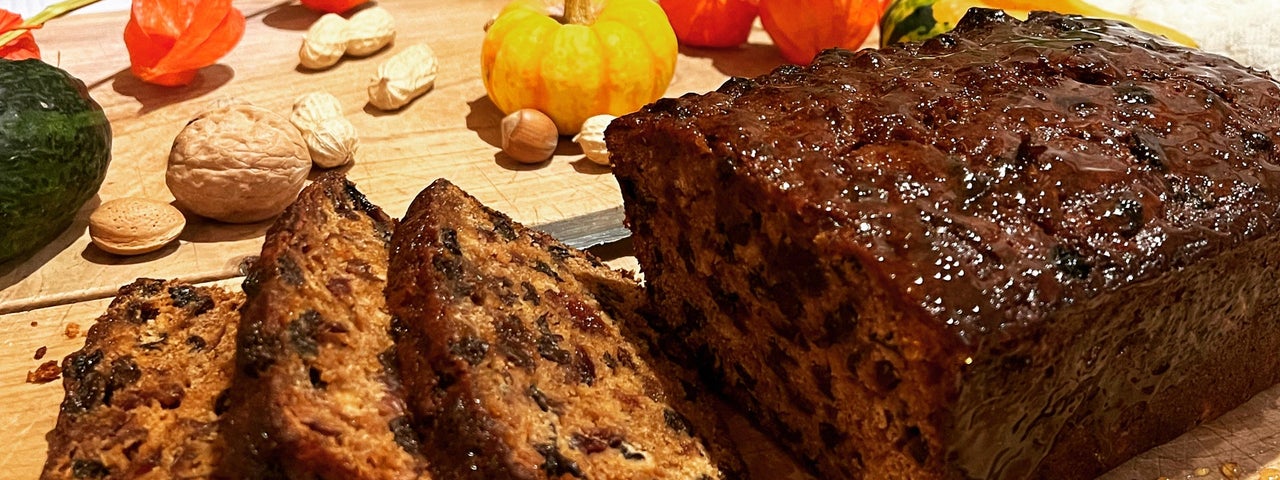 A fruit loaf with some slices cut on a wooden chopping board