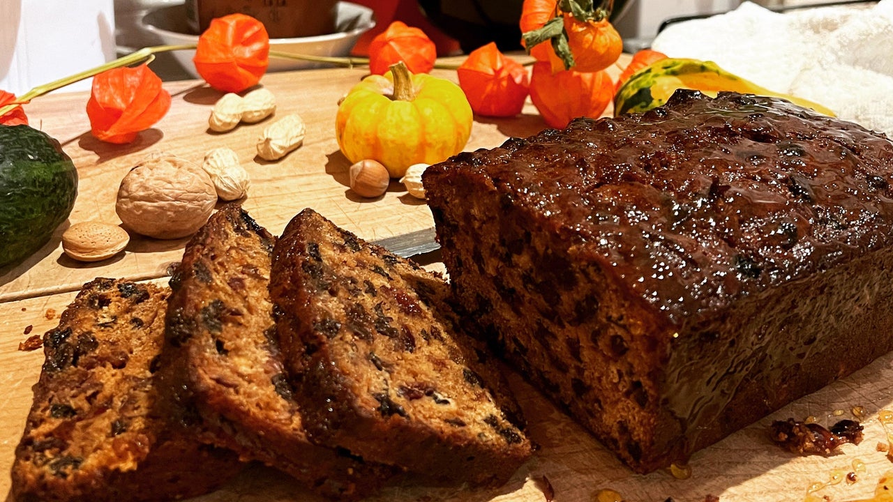 A fruit loaf with some slices cut on a wooden chopping board