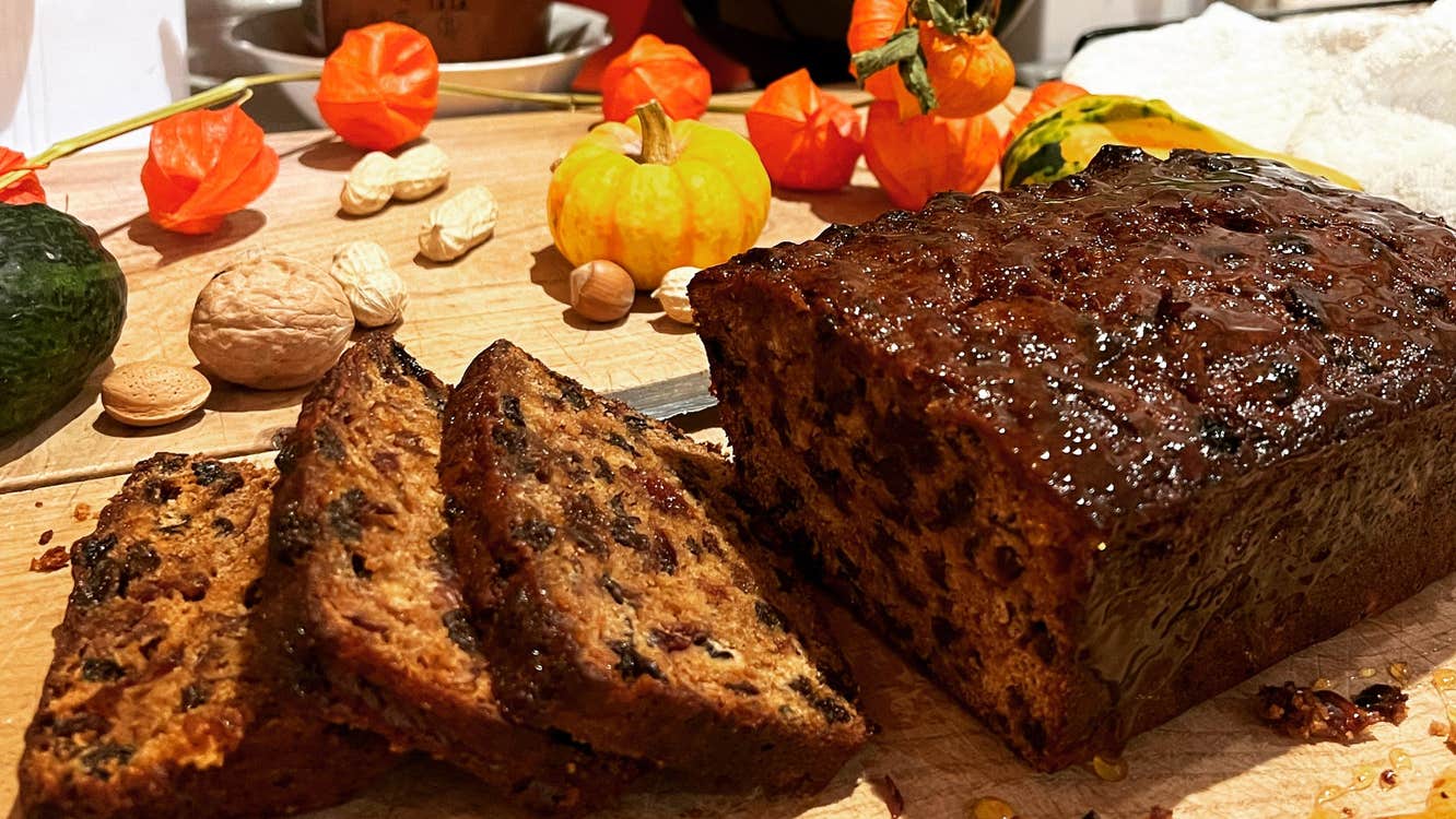 A fruit loaf with some slices cut on a wooden chopping board
