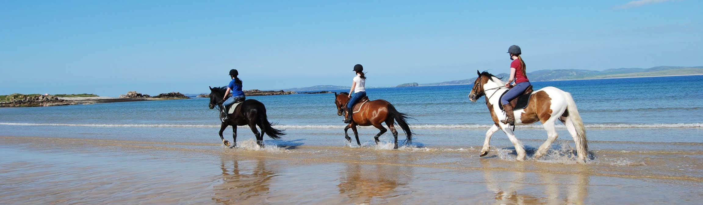 Image of people riding horses on a beach in Clonmany in County Donegal