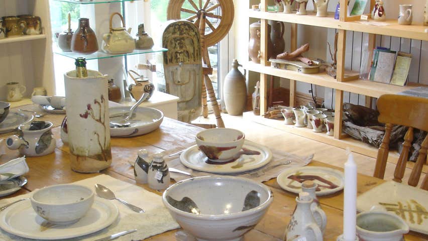 Alan Gaillard Pottery Studio with wooden table and a mix of pottery dishes neatly displayed