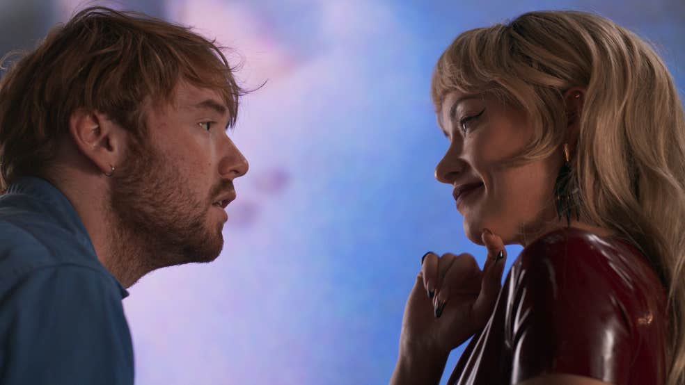 A man looking into the eyes of woman. He seems dishevelled and anxious whereas she seems elegant and confident.