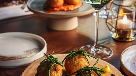 A glass of white wine on a table surrounded by a selection of small plate dishes