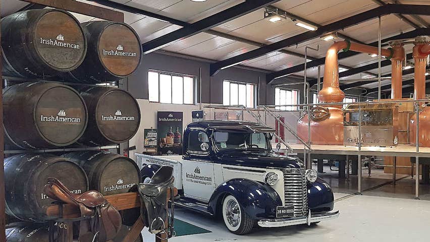 Vintage American car set against the backdrop of the copper distilling pots and stacked whiskey barrels