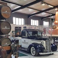 Vintage American car set against the backdrop of the copper distilling pots and stacked whiskey barrels