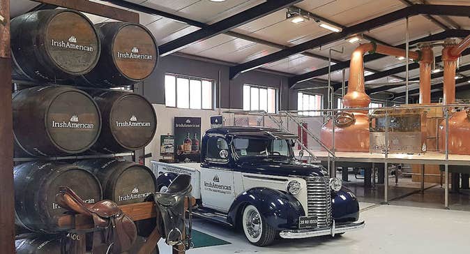 Vintage American car set against the backdrop of the copper distilling pots and stacked whiskey barrels