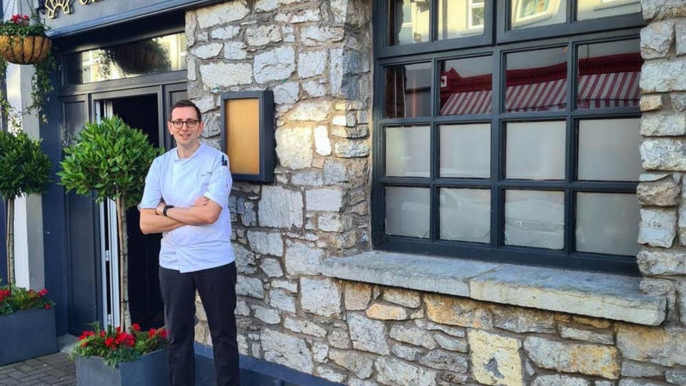 Man in chefs jacket standing outside a restaurant