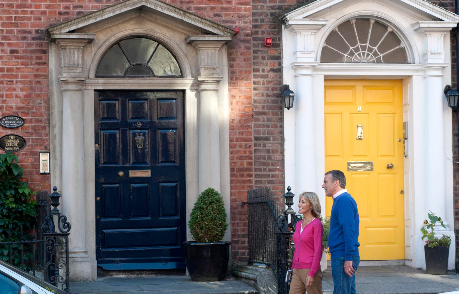Couple walking past Georgian doors in Dublin.