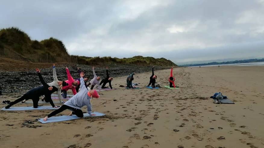 A group of people enjoying a yoga session on the beach in Strandhill, Sligo.