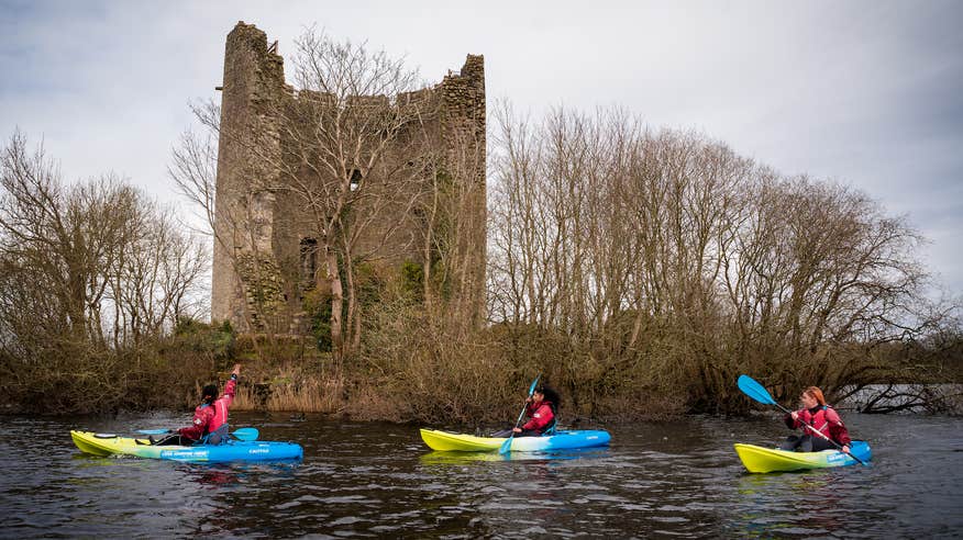People kayaking past Clough Oughter Castle in Cavan