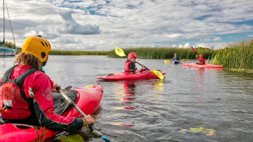 Kayakers in red kayaks paddling near reeds on a Lough Derg County Tipperary