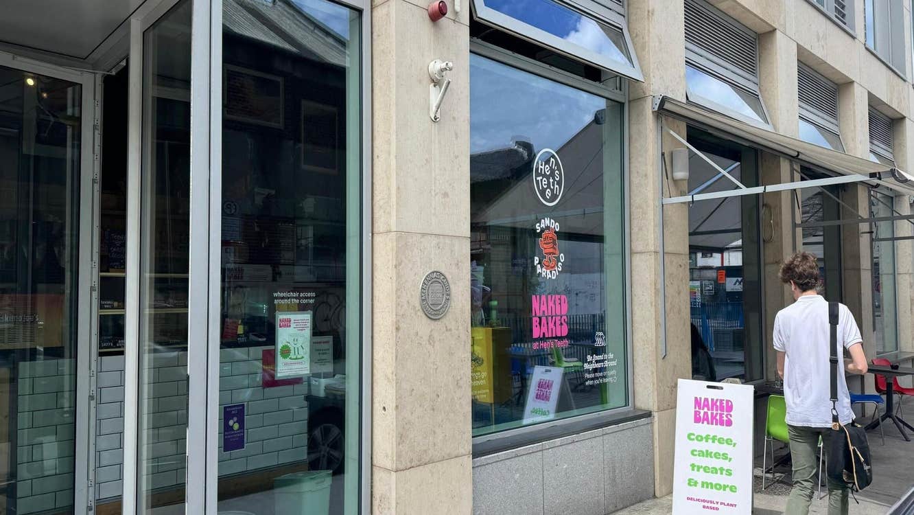 Exterior of a coffee shop with a sandwich board and a person outside