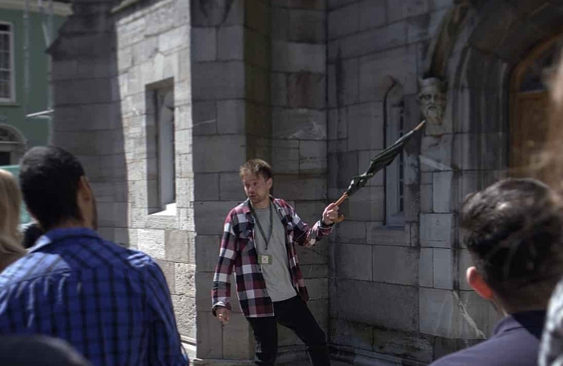 A guide holding an umbrella on tour talking to the group