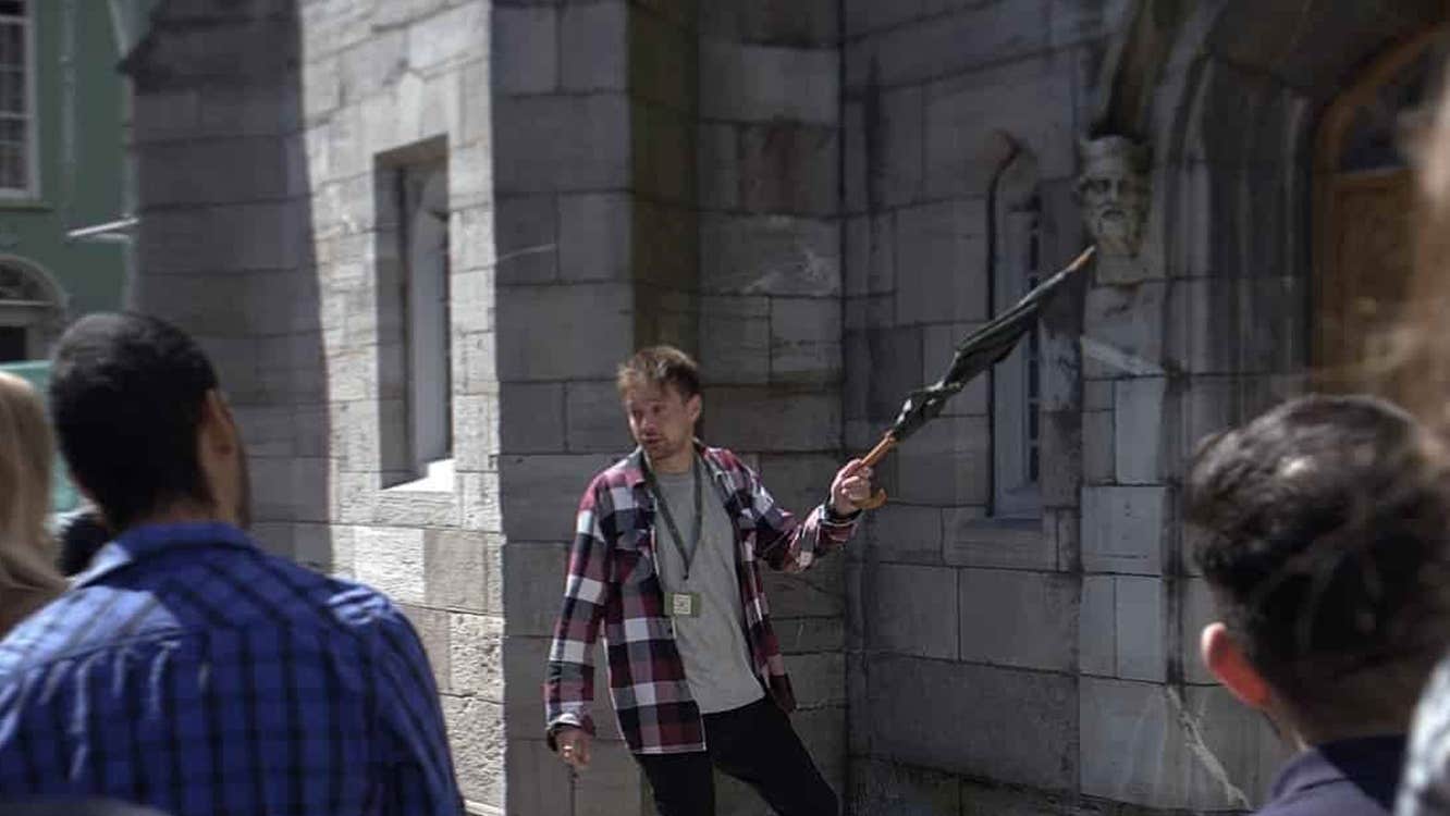 A guide holding an umbrella on tour talking to the group