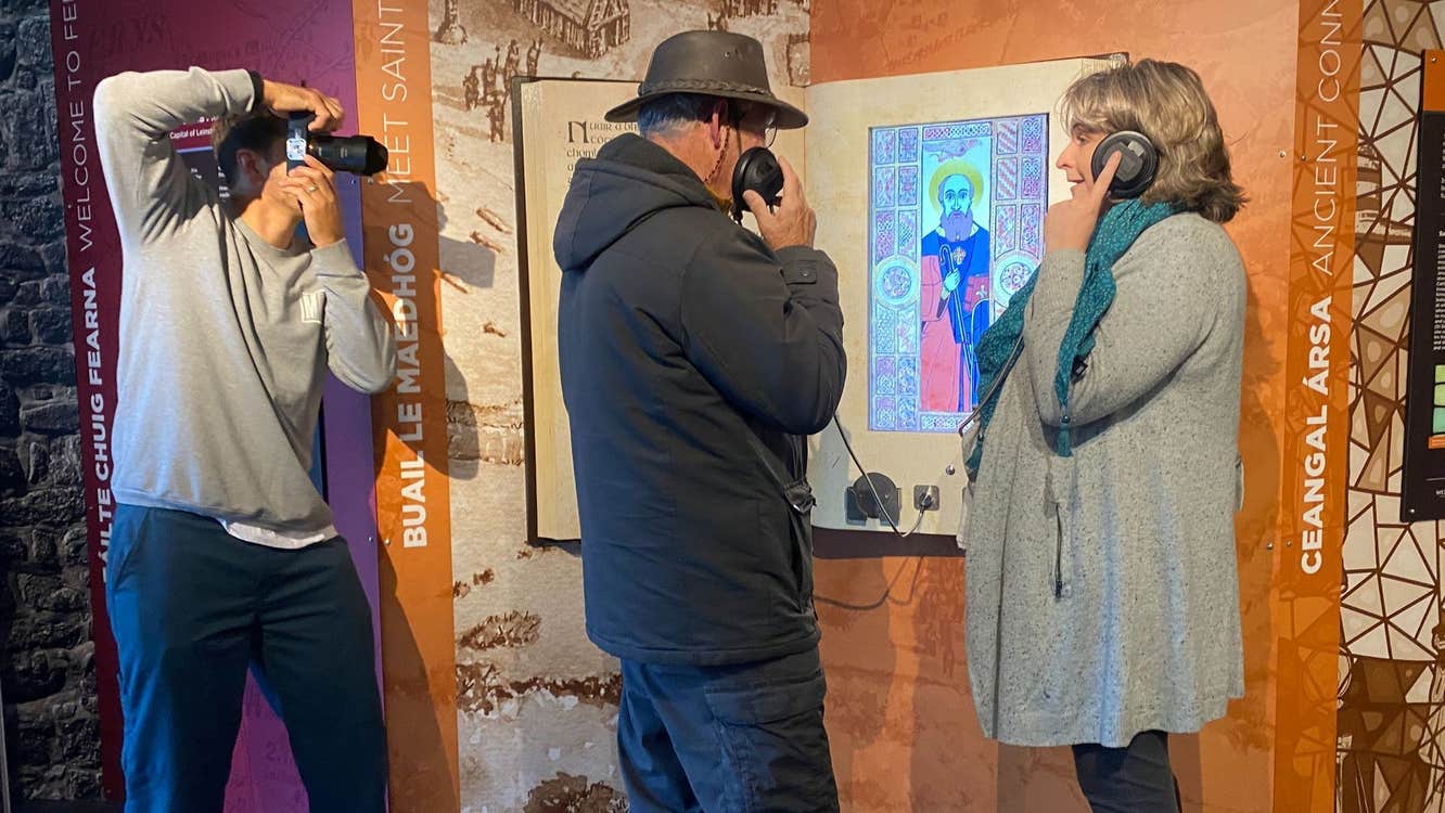 Visitors being photographed using headphones and interactive displays inside a museum