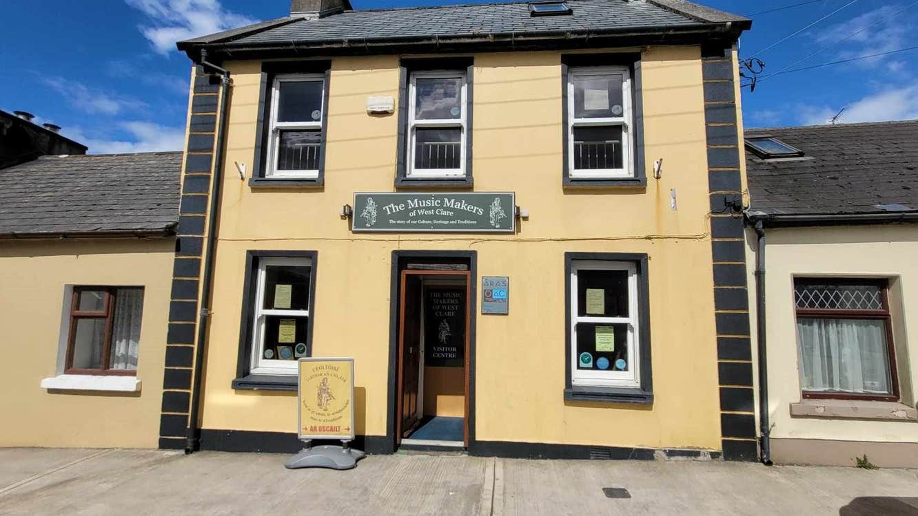 Yellow building on a street with five windows and an open door