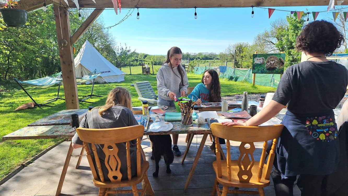 Four people standing around a table with painting materials on a sunny day