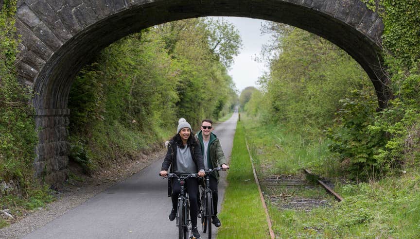 A couple cycling under a bridge on The Old Rail Trail in County Westmeath