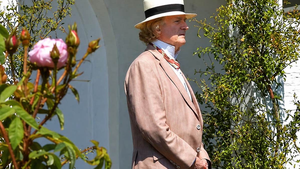 Happy Birthday John McCormack - a man in jacket and straw hat is looking away into the distance with bushes either side of him