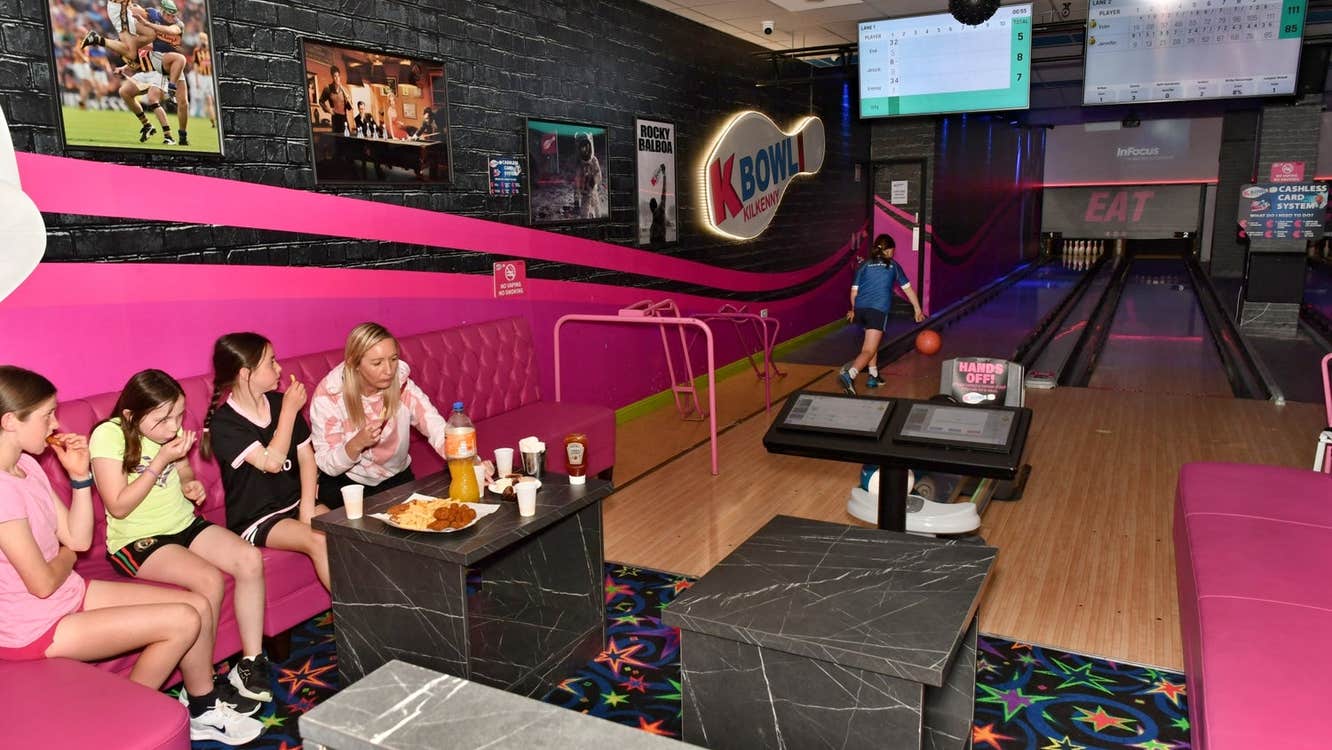 Colourful bowling alley with people sitting while others bowl