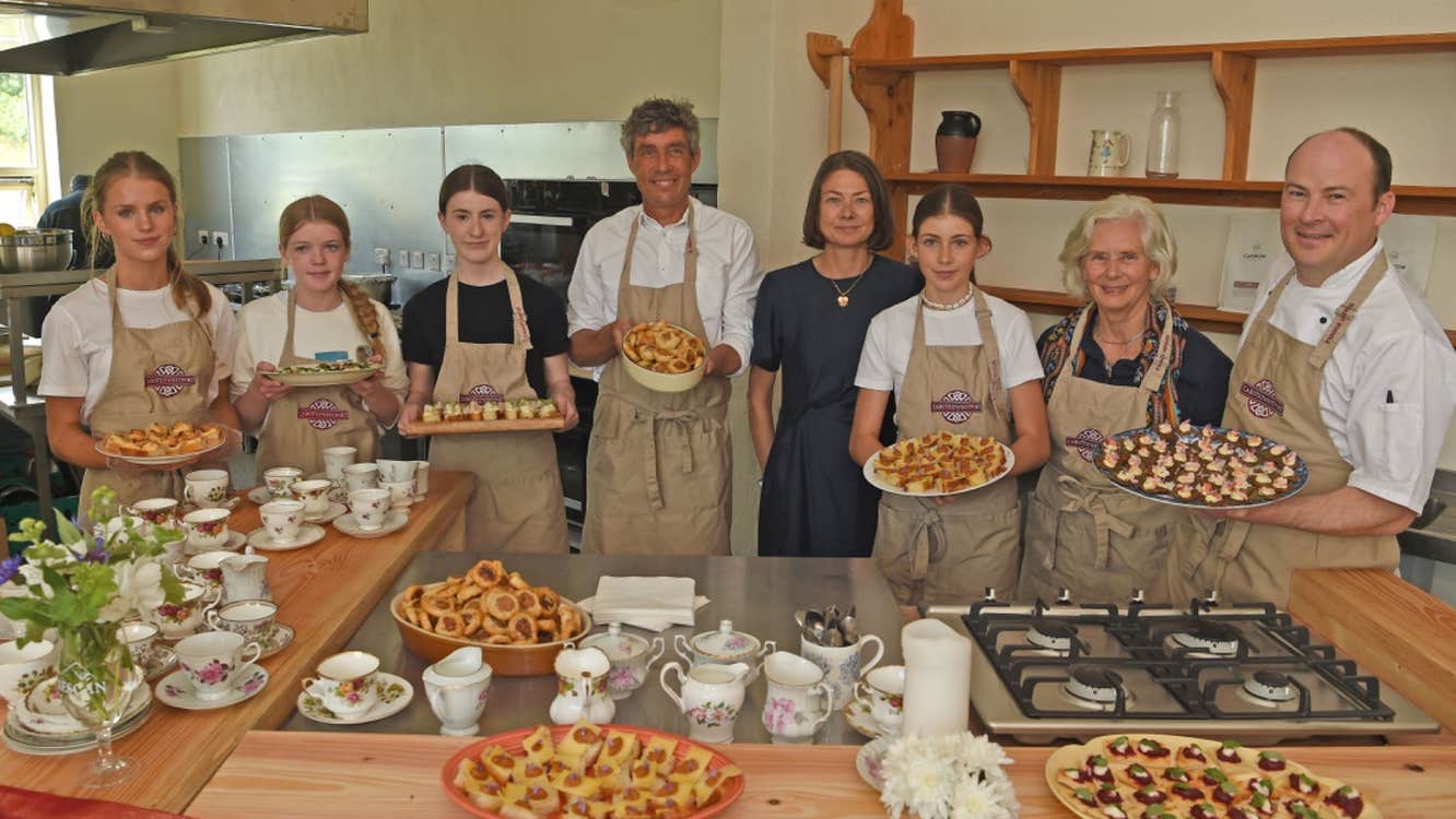 People holding full platters while standing in front of a counter with other baked goods on display