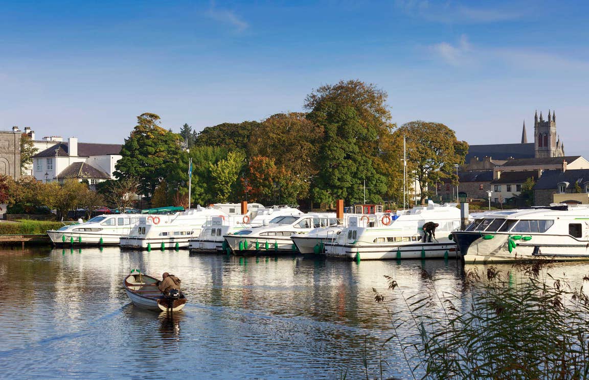 Boats in a marina with a backdrop of trees and a church in Carrick-on-Shannon, County Leitrim