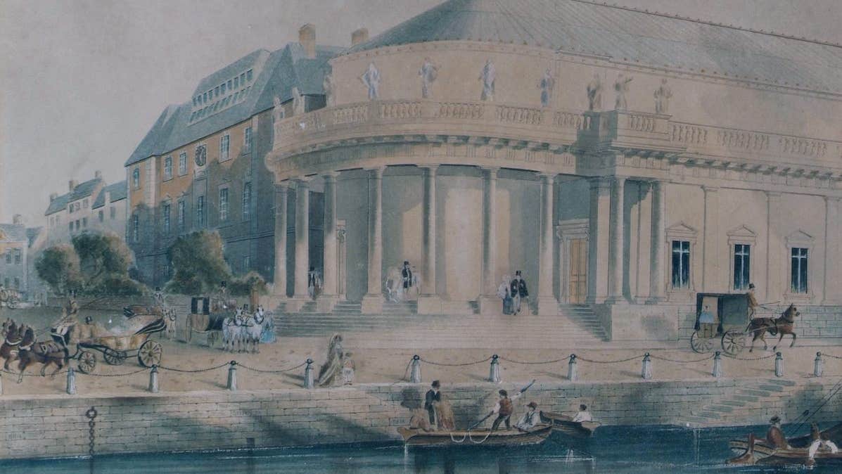 An old drawing showing the Crawford Art Gallery in a previous century with water and a dock outside and horses and carriages.