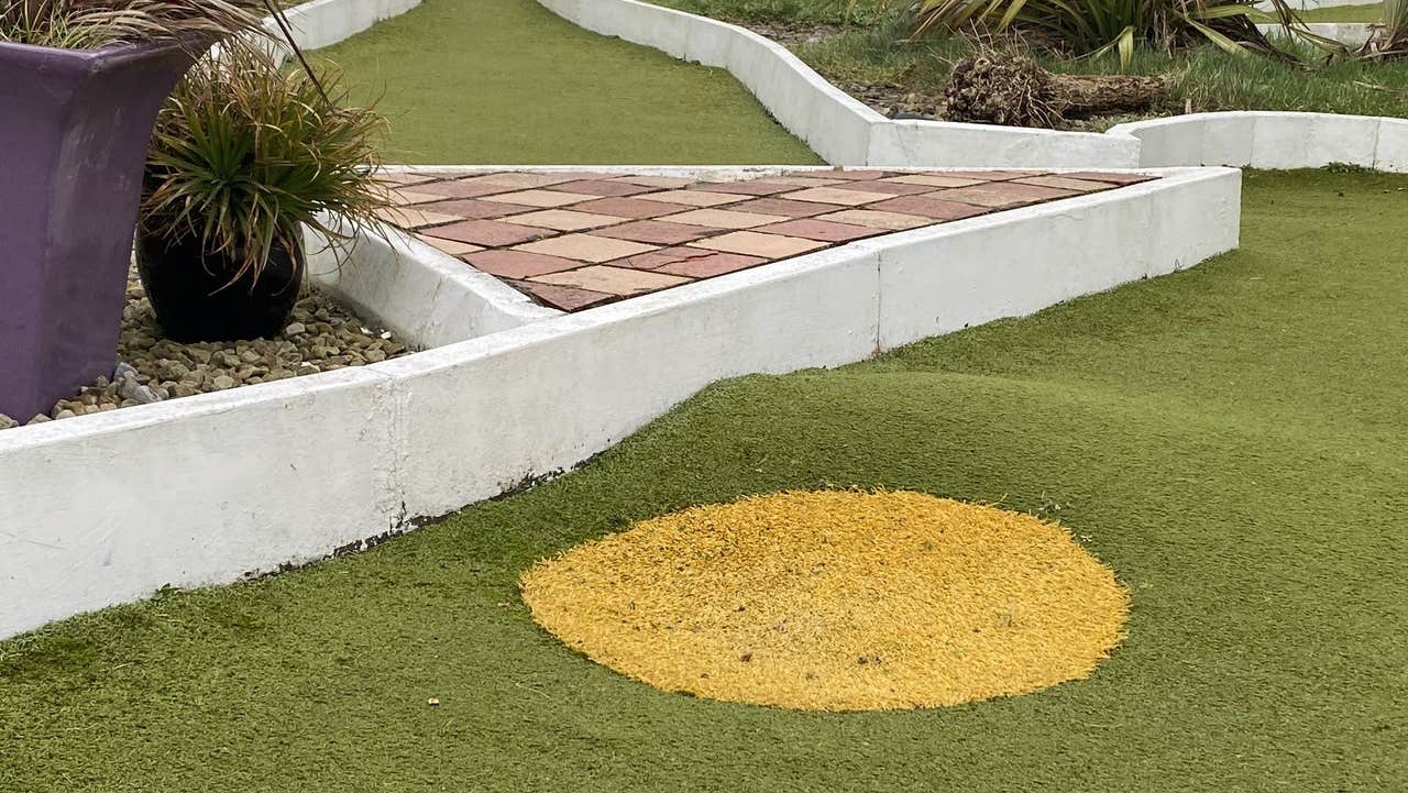 Fake grass and a kerbed obstacle at a crazy golf course