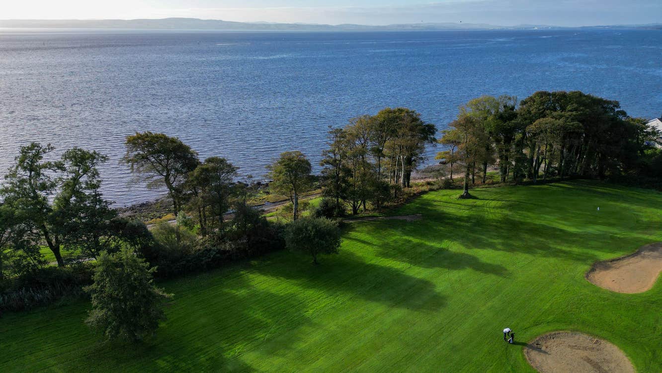 An aerial view of part of a golf club by Lough Foyle showing sand dunes and bordered by trees