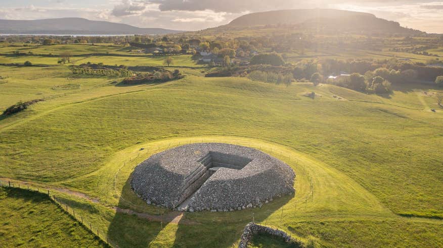 Tombs with mountains and green fields in the background at Carrowmore Megalithic Cemetery, Sligo