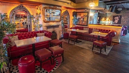 The lounge with red leather sofas and large ornate mirrors hanging on the walls