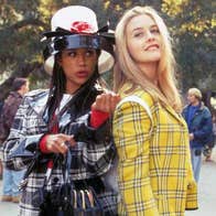 2 young women in different coloured checked outfits standing back to back outdoors