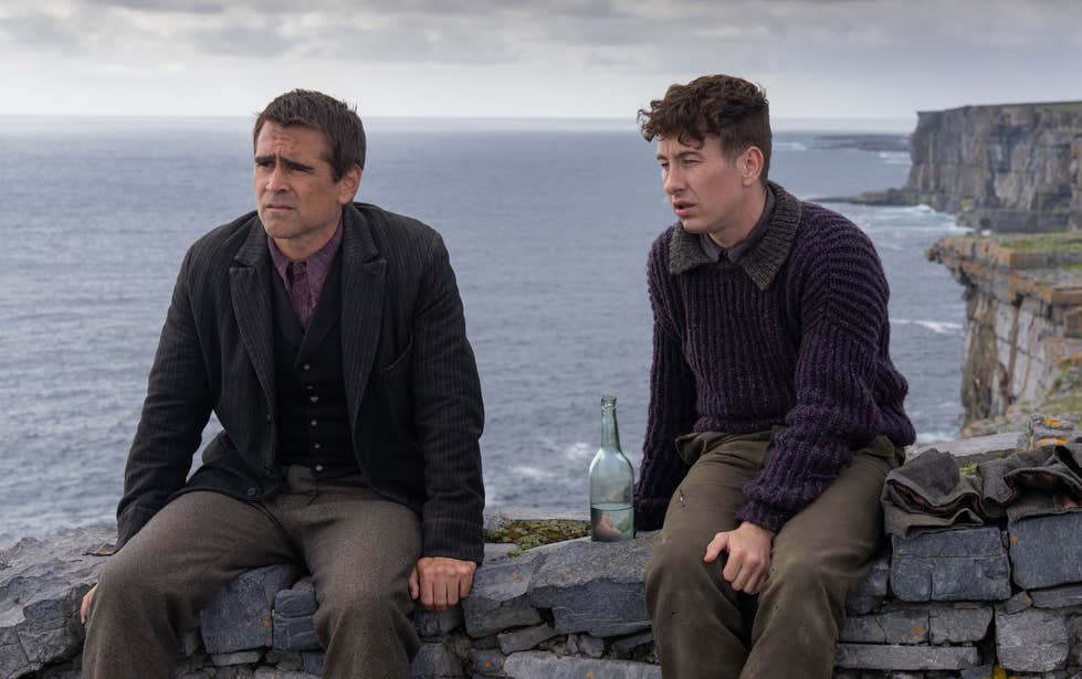 Colin Farrell and Barry Keoghan sit on top of a stone wall on Inis Mor with the Atlantic ocean as the backdrop.