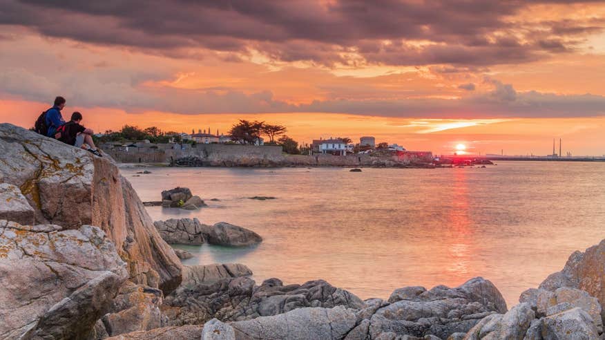 Two people sitting on a rock at Sandycove, Dublin