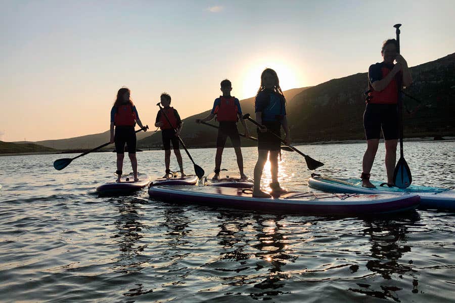Five girls SUPing on the water at sunset