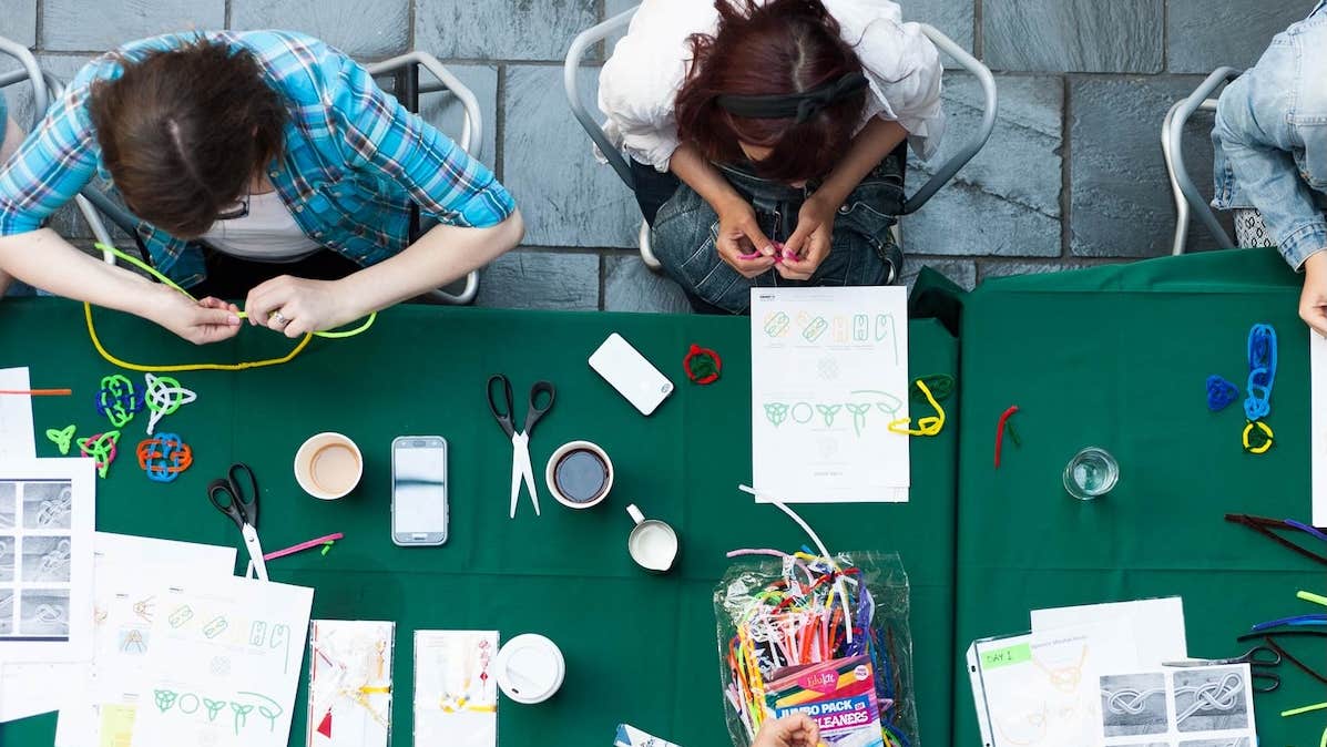 Looking down at people seated at a table covered in craft materials