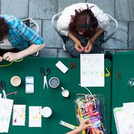 Looking down at people seated at a table covered in craft materials