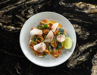 A dish from the menu at Charlotte Quay Restaurant served on a white plate with a slice of lime on the side