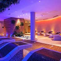 A dimly lit spa with purple lighting and reclined seating