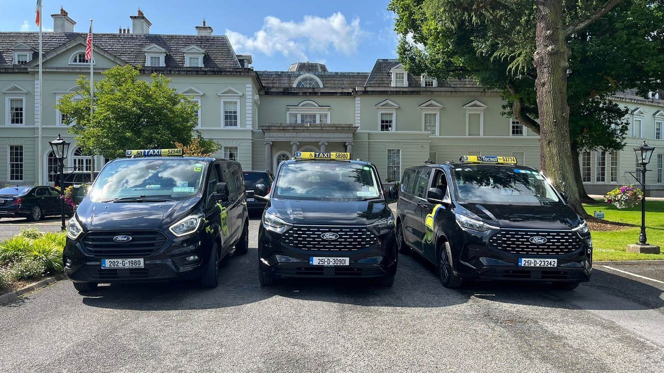 Three black coloured accessible people carrier taxis lined up in a row