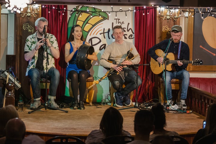 Four musicians playing instruments on a stage at the Irish House Party
