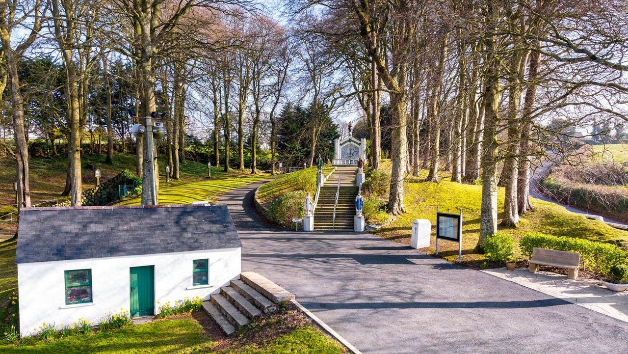 Entrance to a shrine with trees and a miniature traditional cottage