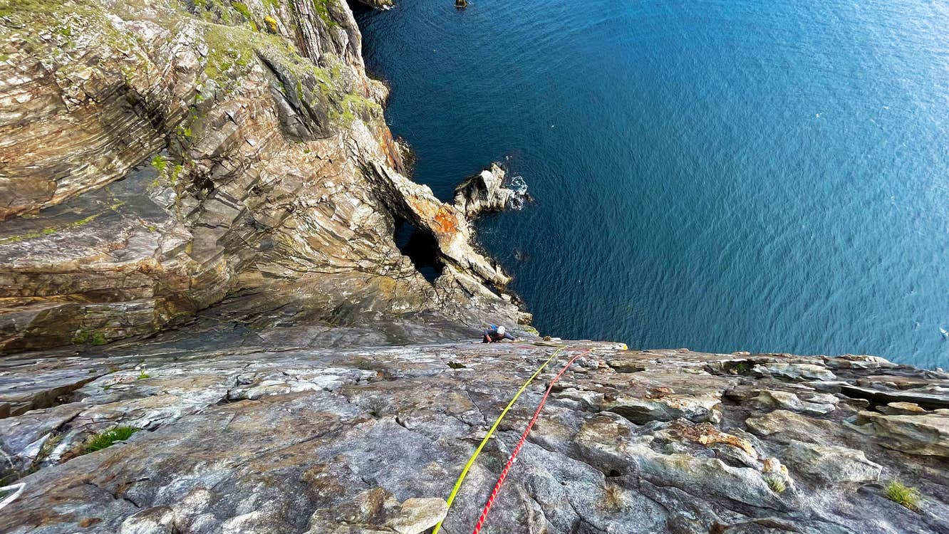 Carraig Climbing view of ropes hanging down a cliff face to the water